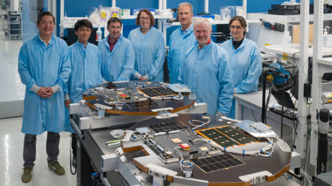 Engineers from The Aerospace Corporation conduct final checks on two flat, circular DiskSat spacecraft before launch on a NASA demonstration mission.