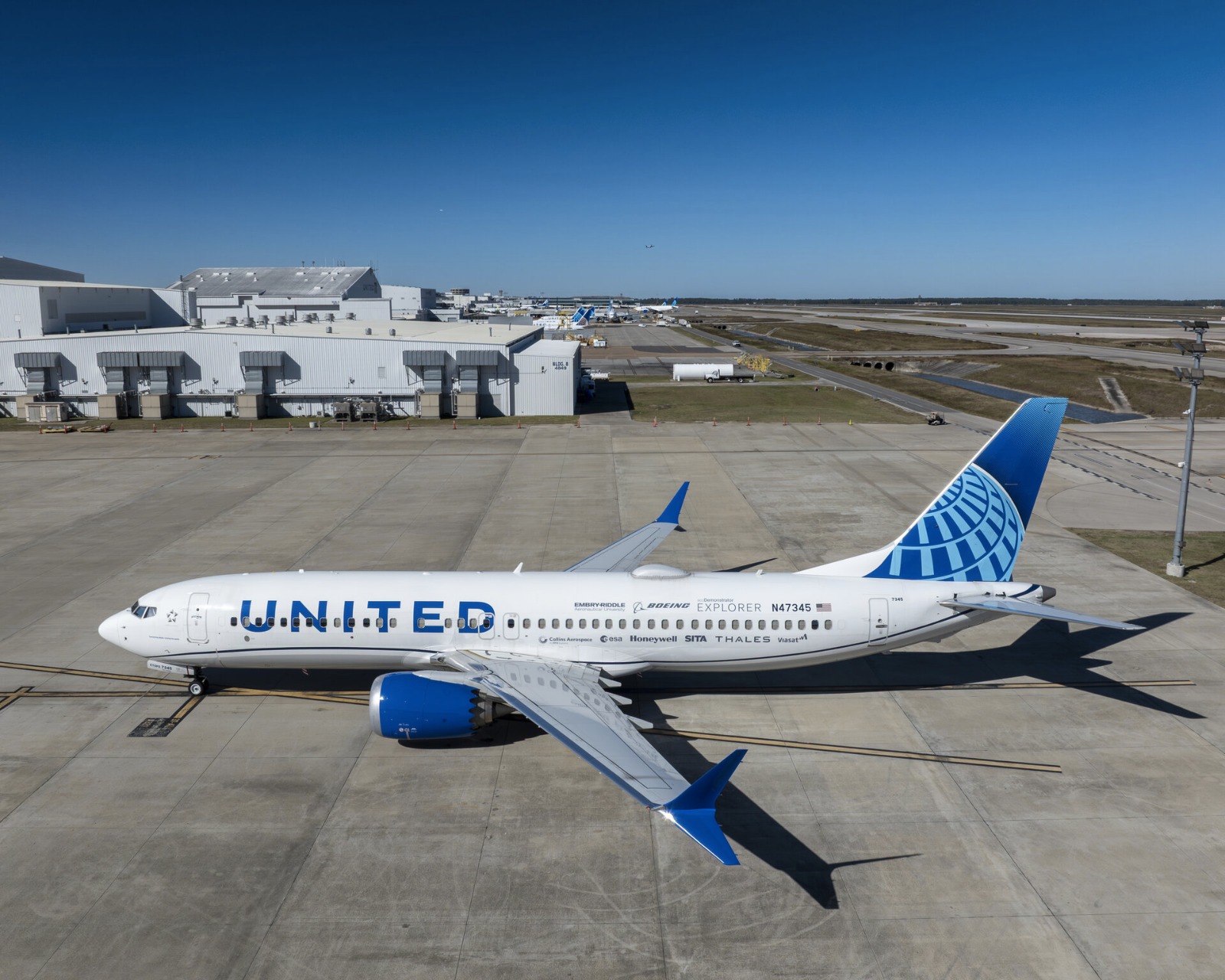 A Boeing passenger aircraft flying at cruising altitude with digital data link lines connecting it to a satellite in space.