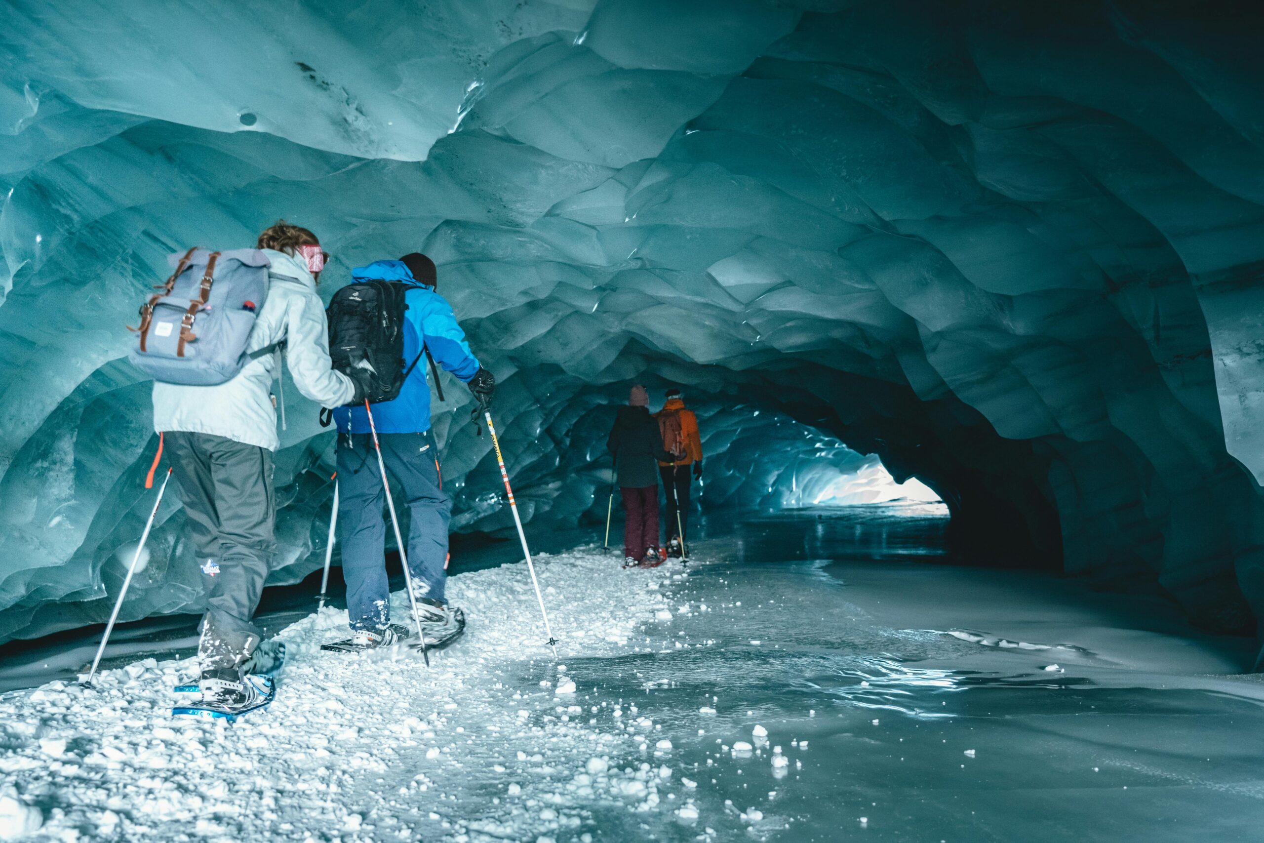Chinese astronauts wearing headlamps and gear conducting mapping training inside a dark, rocky cave.